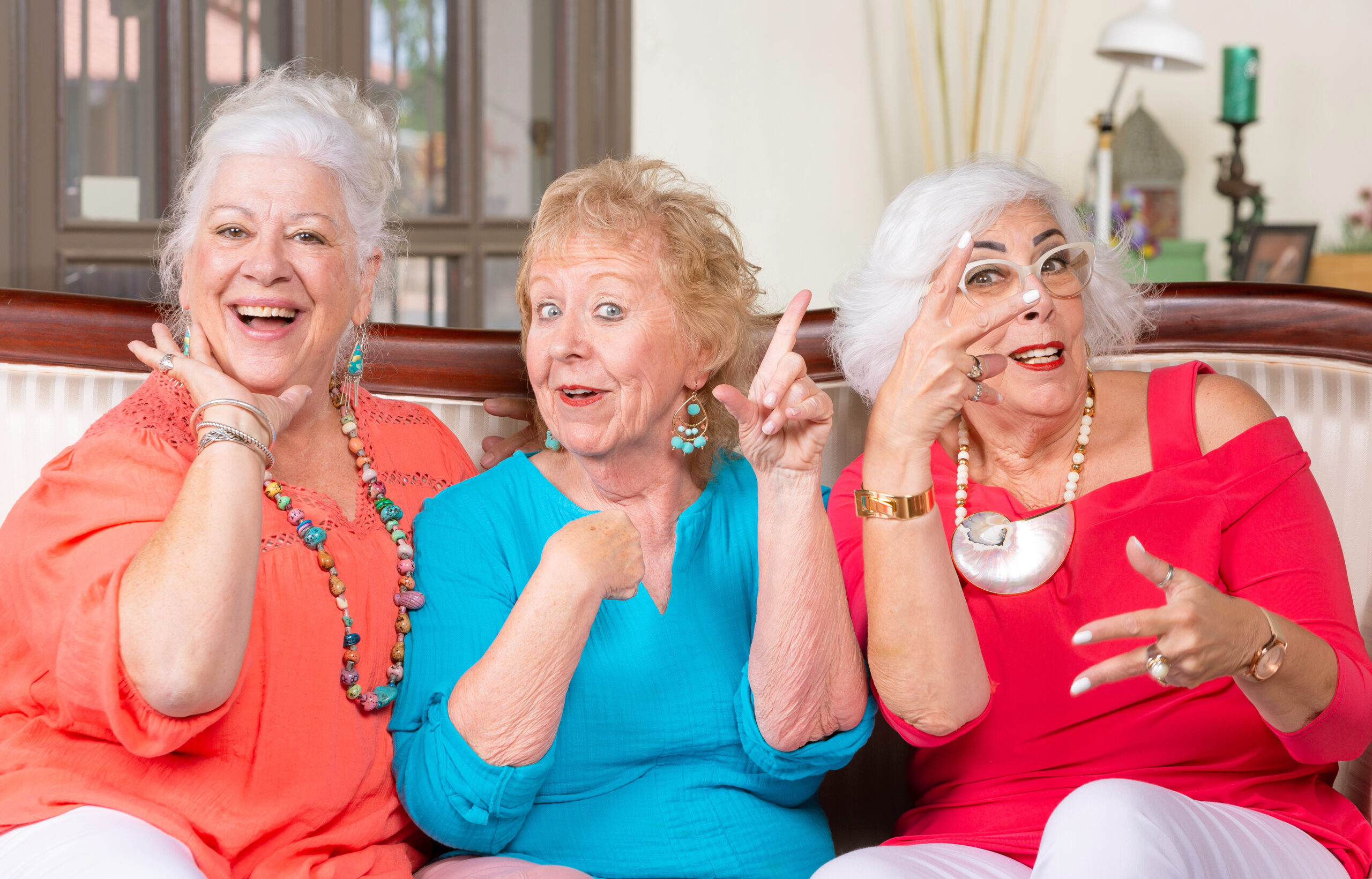 Three senior ladies in bright colored clothes vamping and posing